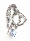 A silver necklace with blue glass heart