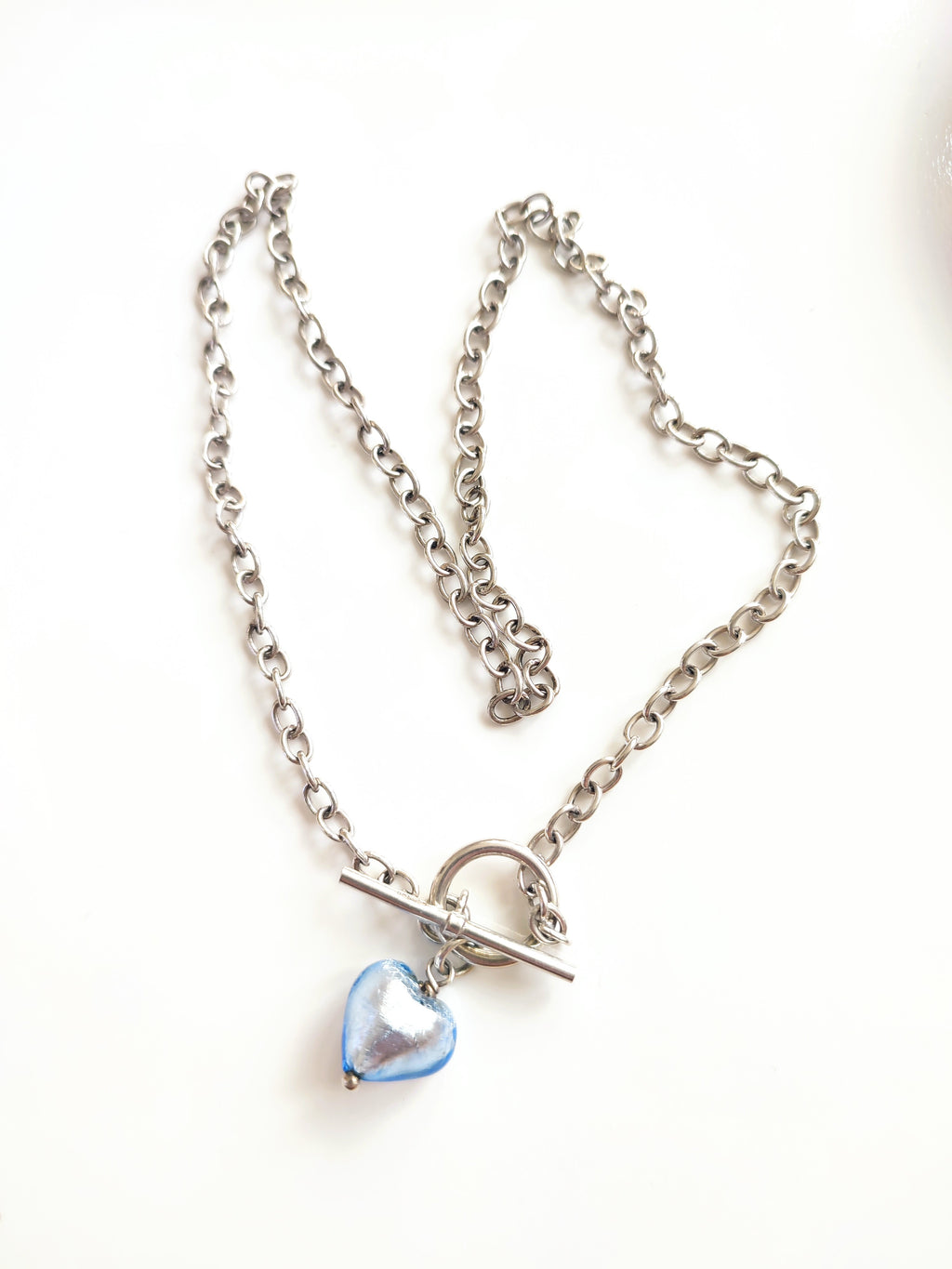 A silver necklace with blue glass heart