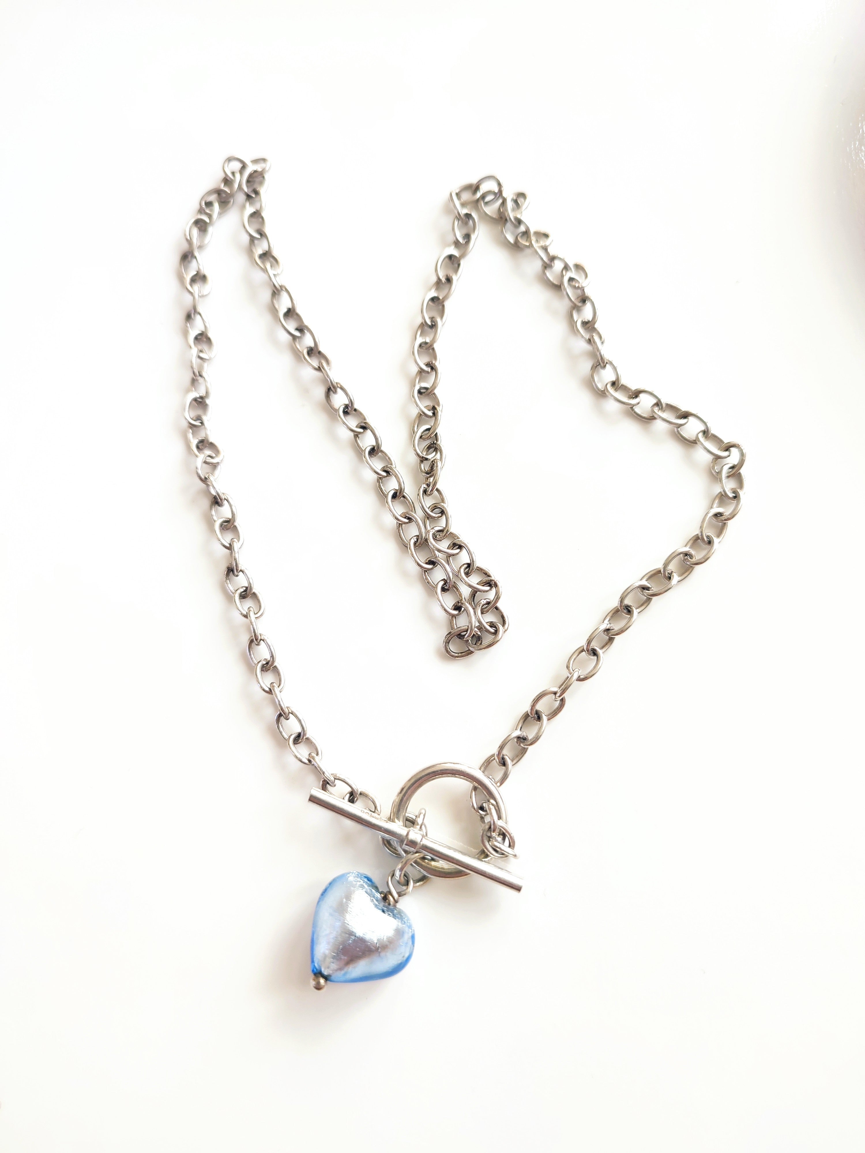 A silver necklace with blue glass heart