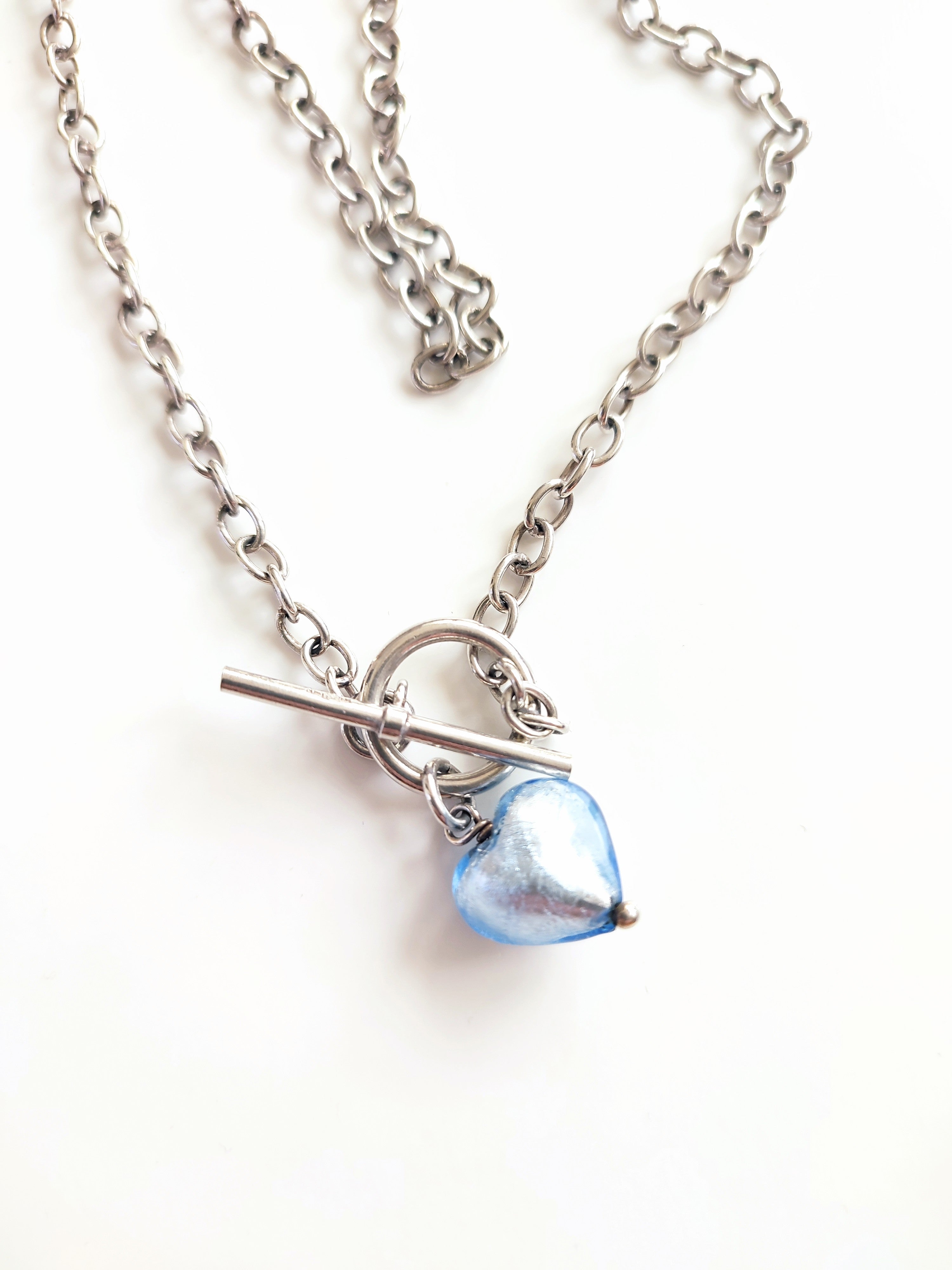 A silver necklace with blue glass heart