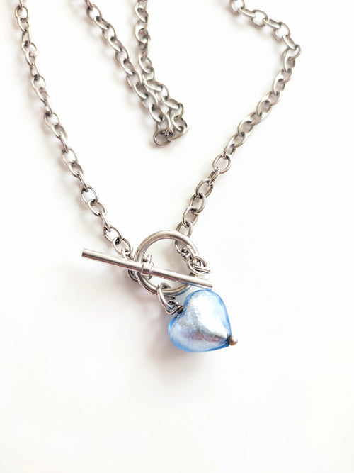 A silver necklace with blue glass heart